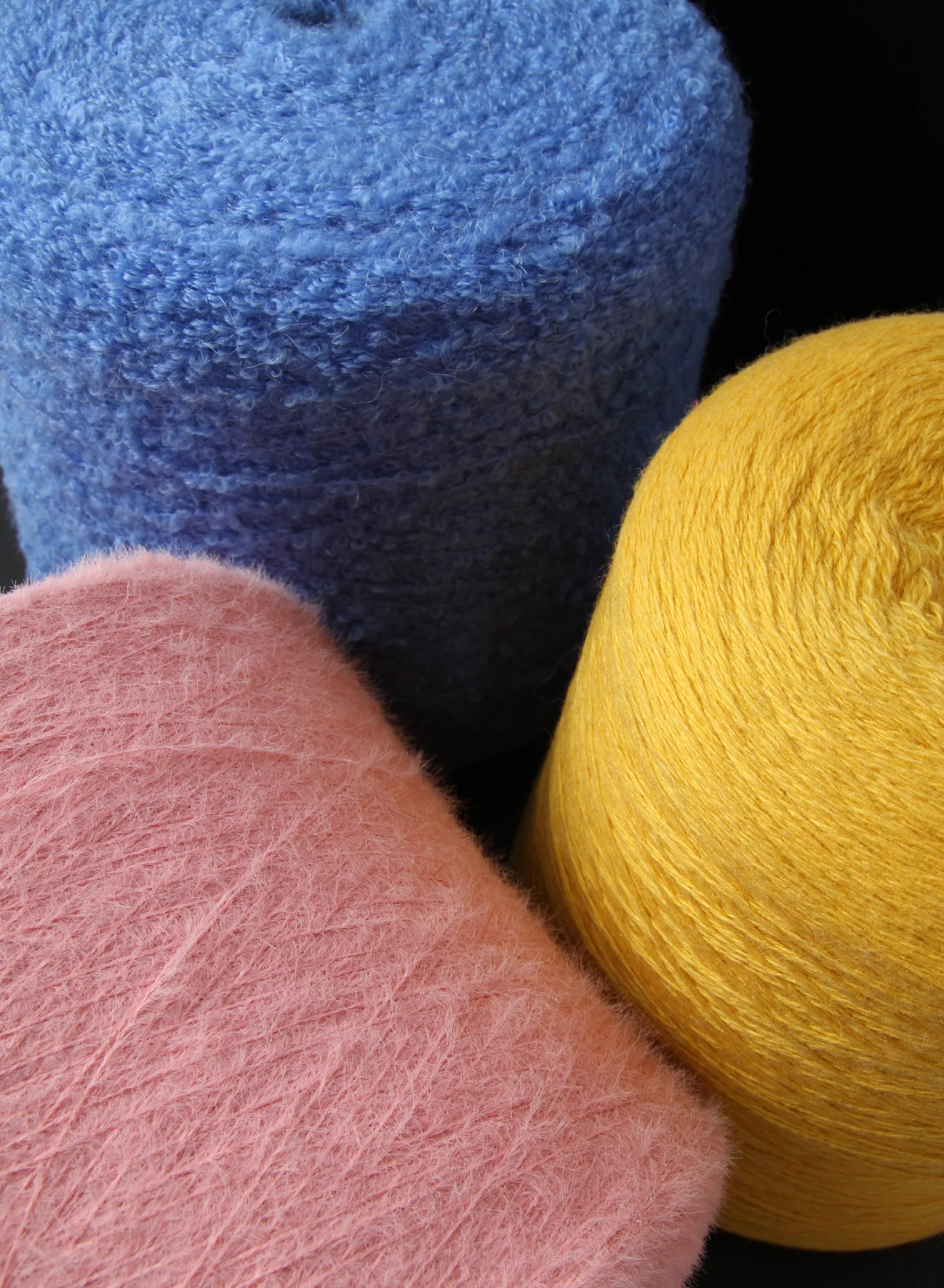 Blue, pink and yellow fuzzy yarn cones in a client-supplied photograph
